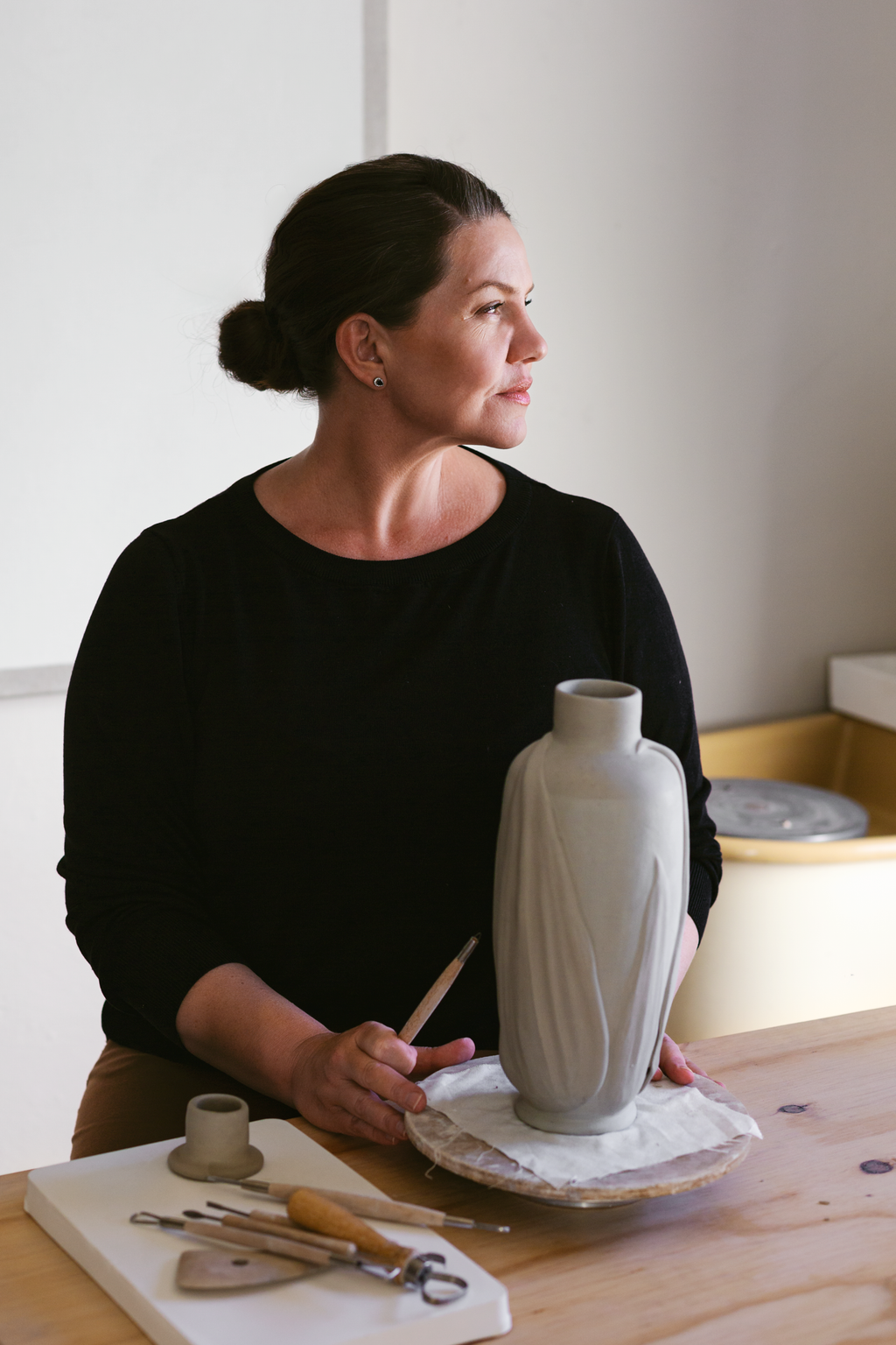 Person holding a ceramic vase in a pottery studio