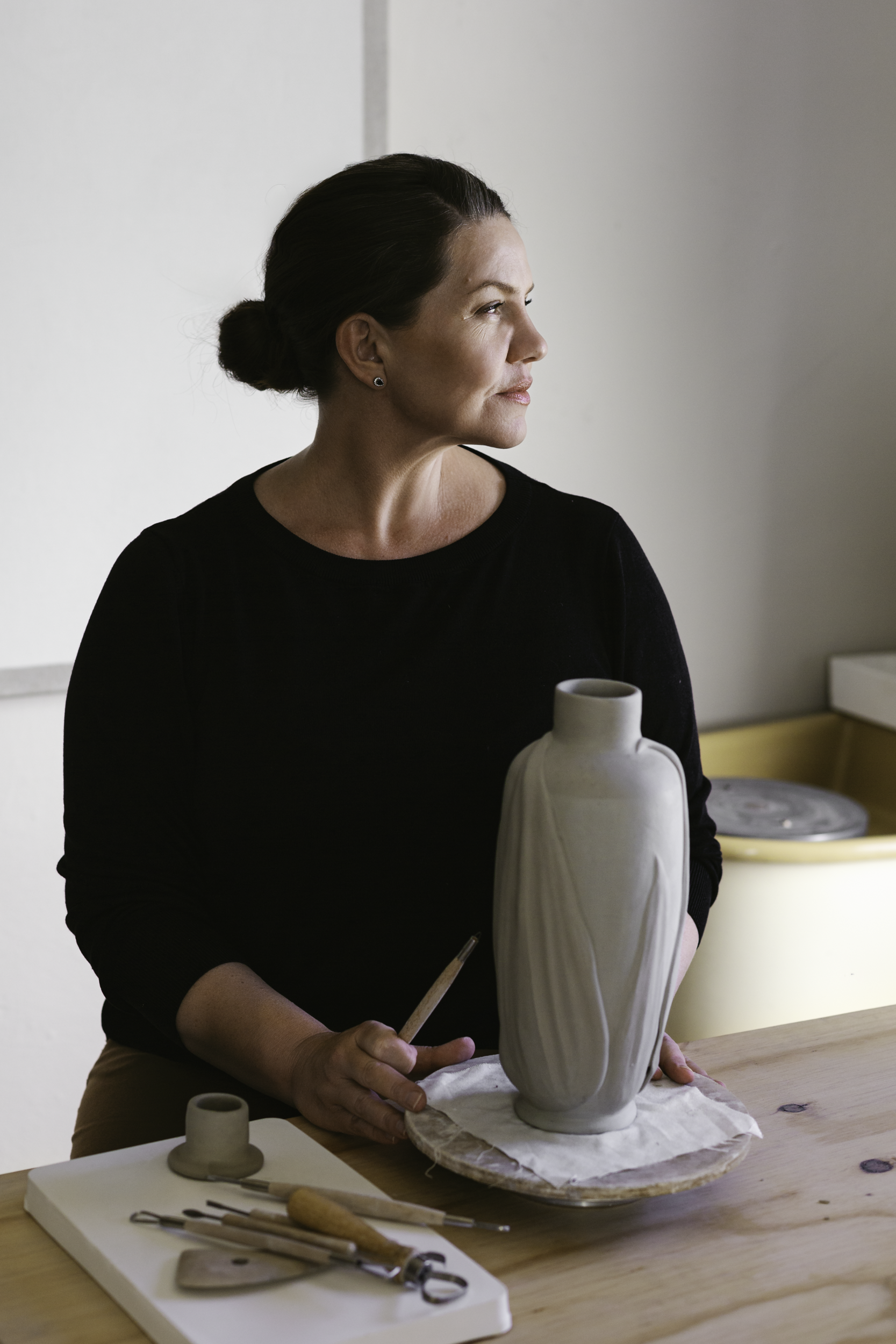 Person holding a ceramic vase in a pottery studio